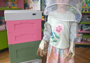 Dziewczynka w różowej spódniczce w stroju pszczelarza